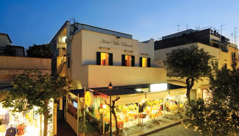 Hotel Villa Diana a Ischia, con un ristorante all'aperto illuminato e negozi.