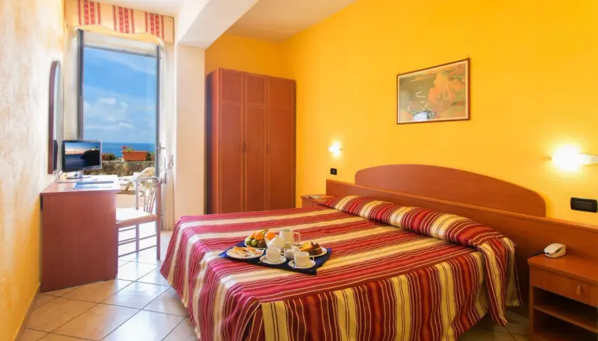 Camera accogliente con vista mare all'Hotel Parco dei Principi Ischia. Colazione servita sul letto, pronta per iniziare la giornata.