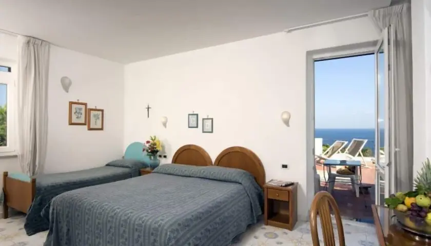 Camera con due letti singoli e un letto matrimoniale, con vista mare dal balcone. L'Hotel Gemma offre un soggiorno rilassante.