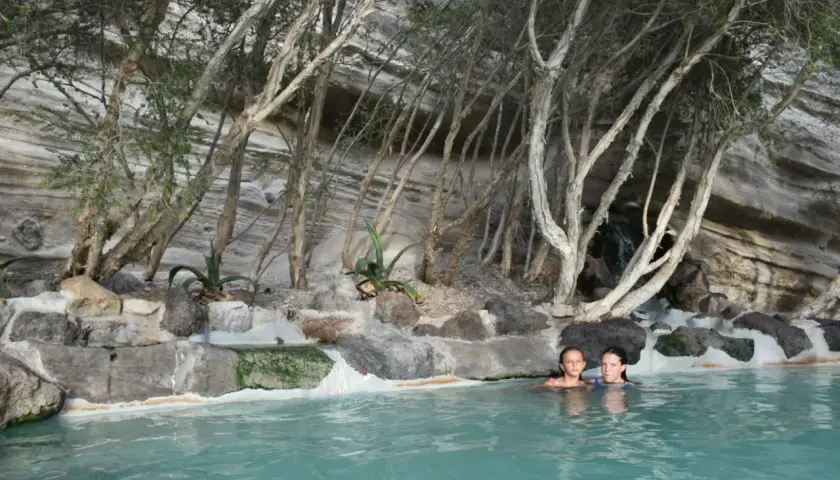 Due bambine si godono un bagno rilassante in una piscina naturale, circondata da rocce e vegetazione, un luogo perfetto per terme gratuite.