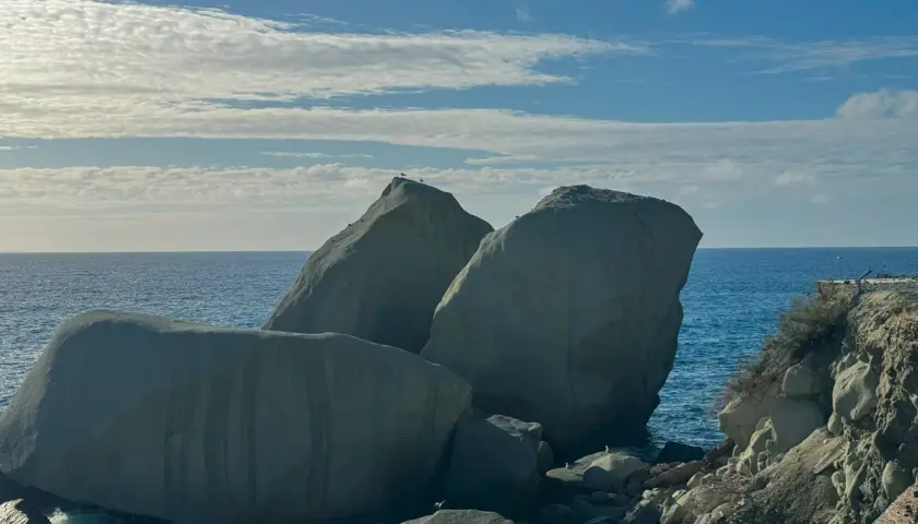 Scogli degli innamorati baciati dal sole, con il mare blu e nuvole bianche nel cielo.