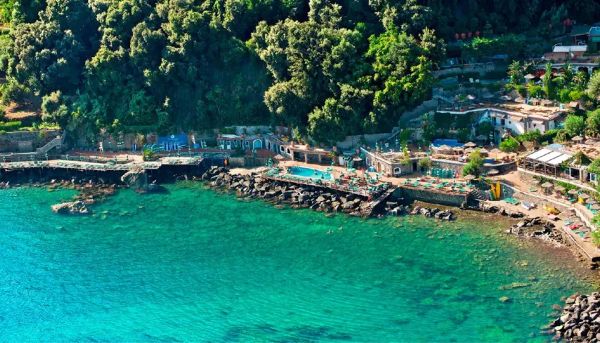 Un incantevole **bagnitiello a Ischia**, con acque cristalline, una piscina panoramica e una lussureggiante vegetazione che abbraccia la costa rocciosa.