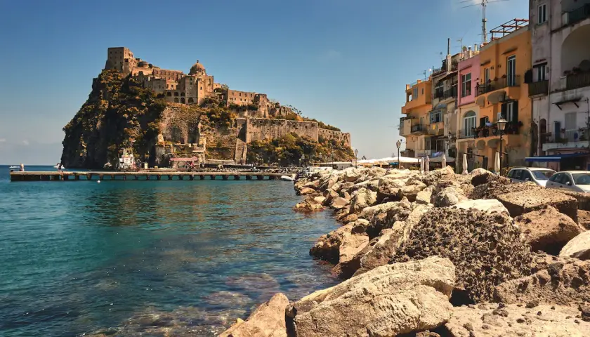 Castello Aragonese su uno scoglio, case colorate e mare cristallino. Chissà come si chiamano gli abitanti di Ischia, i veri protagonisti di questo scorcio.