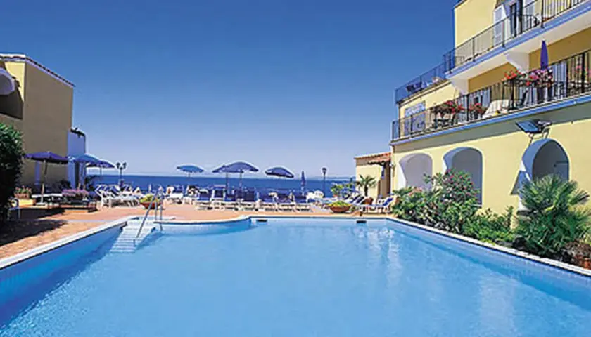 Piscina e mare azzurri al **hotel Parco Aurora Terme Ischia**. Lettini e ombrelloni invitano al relax.