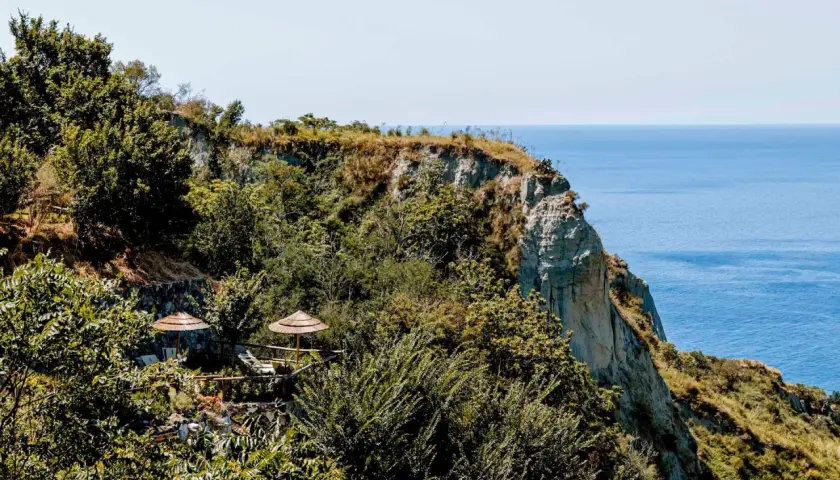 Terrazza panoramica con ombrelloni di paglia e vista sul mare a Nitrodi, Ischia.