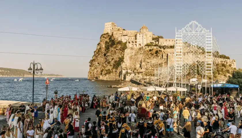 Festa in costume sul lungomare, con il castello sullo sfondo. La spiaggia degli inglesi è animata da figuranti e spettatori.
