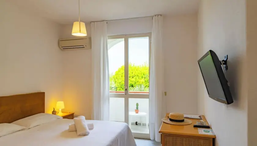 Camera accogliente al paradise relais villa janto, con letto comodo, TV e balcone con vista sul verde.