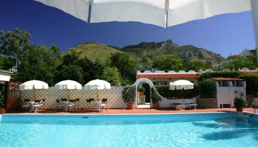 Piscina e tavoli all'aperto con vista sulle montagne, un angolo di relax all'hotel Lord Byron Forio.