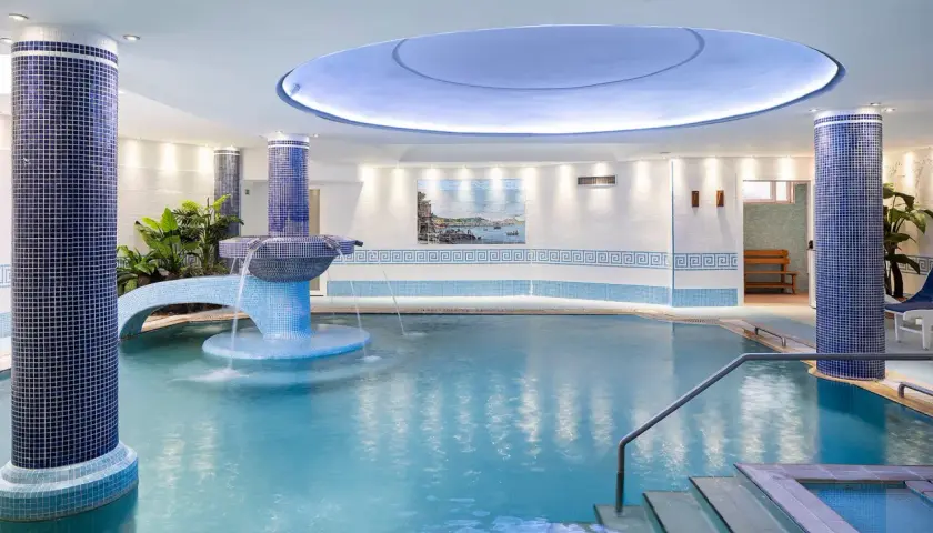 Piscina interna con cascata e piante, un'oasi di relax in uno spa a Ischia.