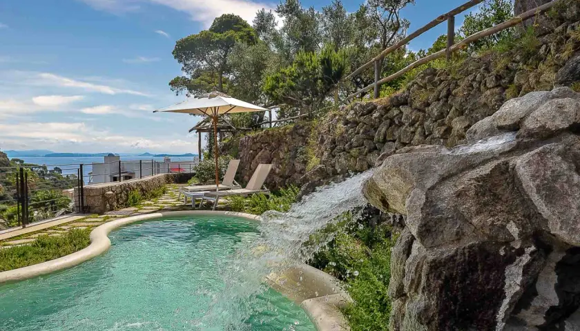 Piscina con cascata e vista mare, ideale per scoprire cosa curano le terme di Ischia. Relax e benessere assicurati.