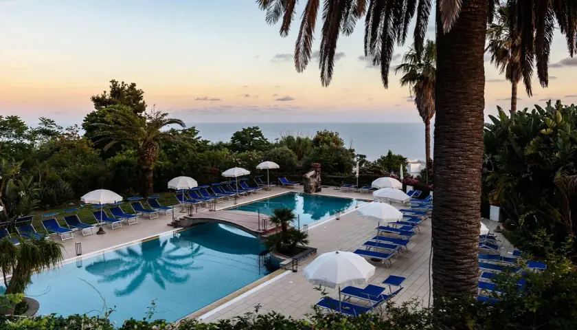 Piscina con lettini e ombrelloni al tramonto, vista mare. Un'oasi di relax all'Hotel Calitto Ischia.