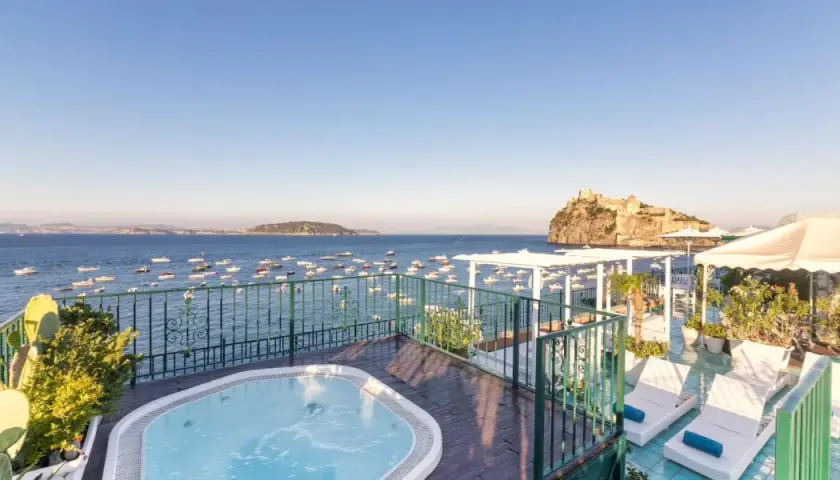 Terrazza con vasca idromassaggio e vista sul mare, barche e il Castello Aragonese. Un sogno al **Hotel Miramare e Castello Ischia**.