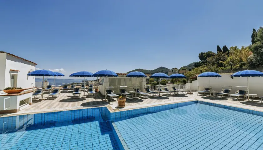 Piscina e lettini sotto ombrelloni blu al **hotel villa d'Orta Casamicciola**. Vista mare e collina.