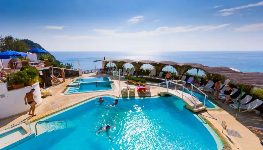 Relax in piscina con vista mare, un sogno a San Valentino Terme. Persone nuotano e si godono il sole.