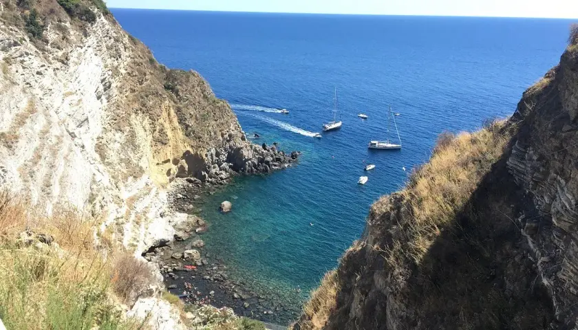 Baia di Panza, Ischia: scogliere a picco sul mare blu, barche a vela e un angolo di paradiso per nuotare.