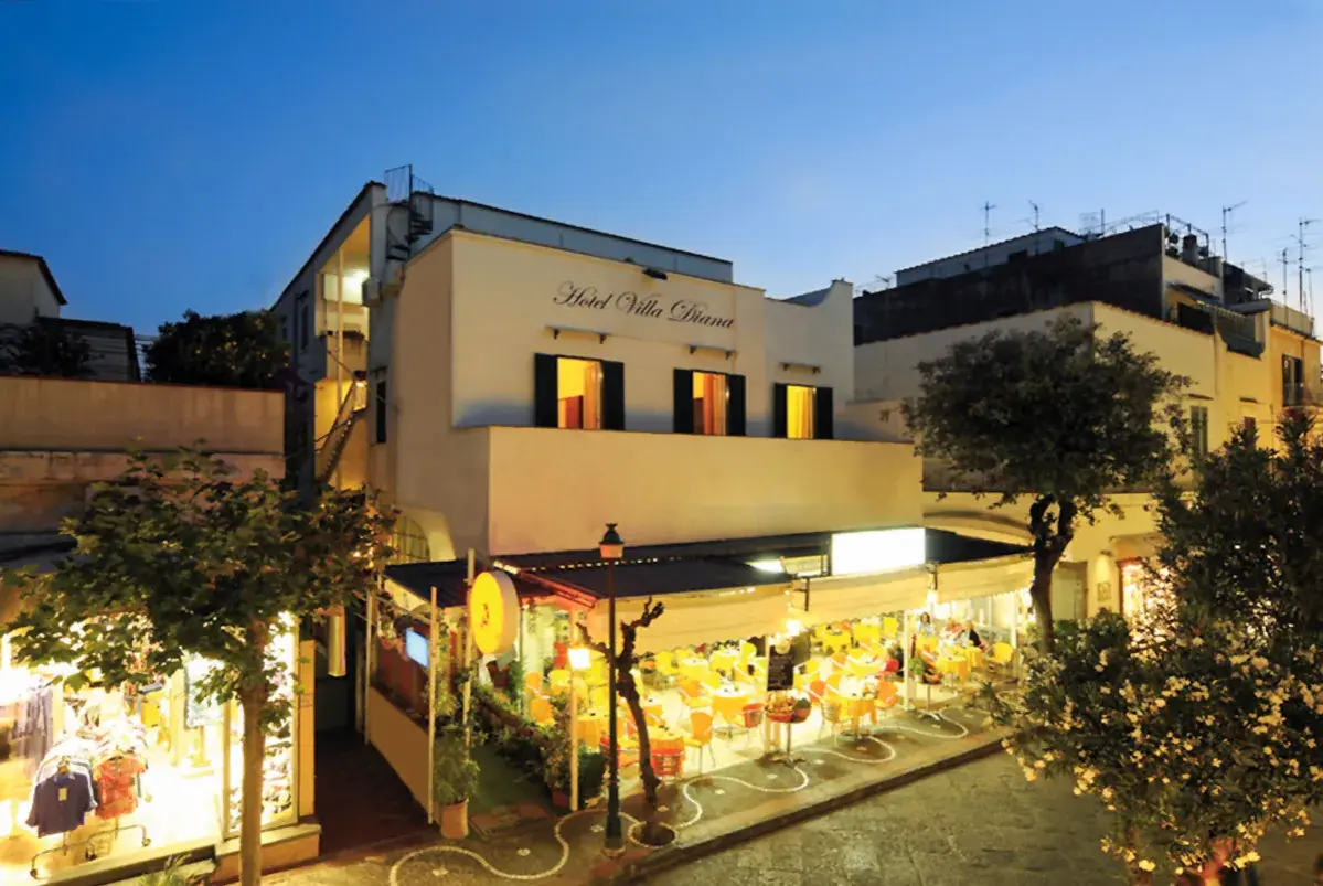 Hotel Villa Diana a Ischia, con un ristorante all'aperto illuminato e negozi.