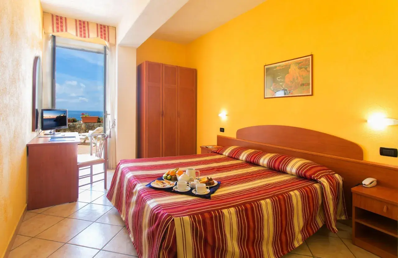 Camera accogliente con vista mare all'Hotel Parco dei Principi Ischia. Colazione servita sul letto, pronta per iniziare la giornata.