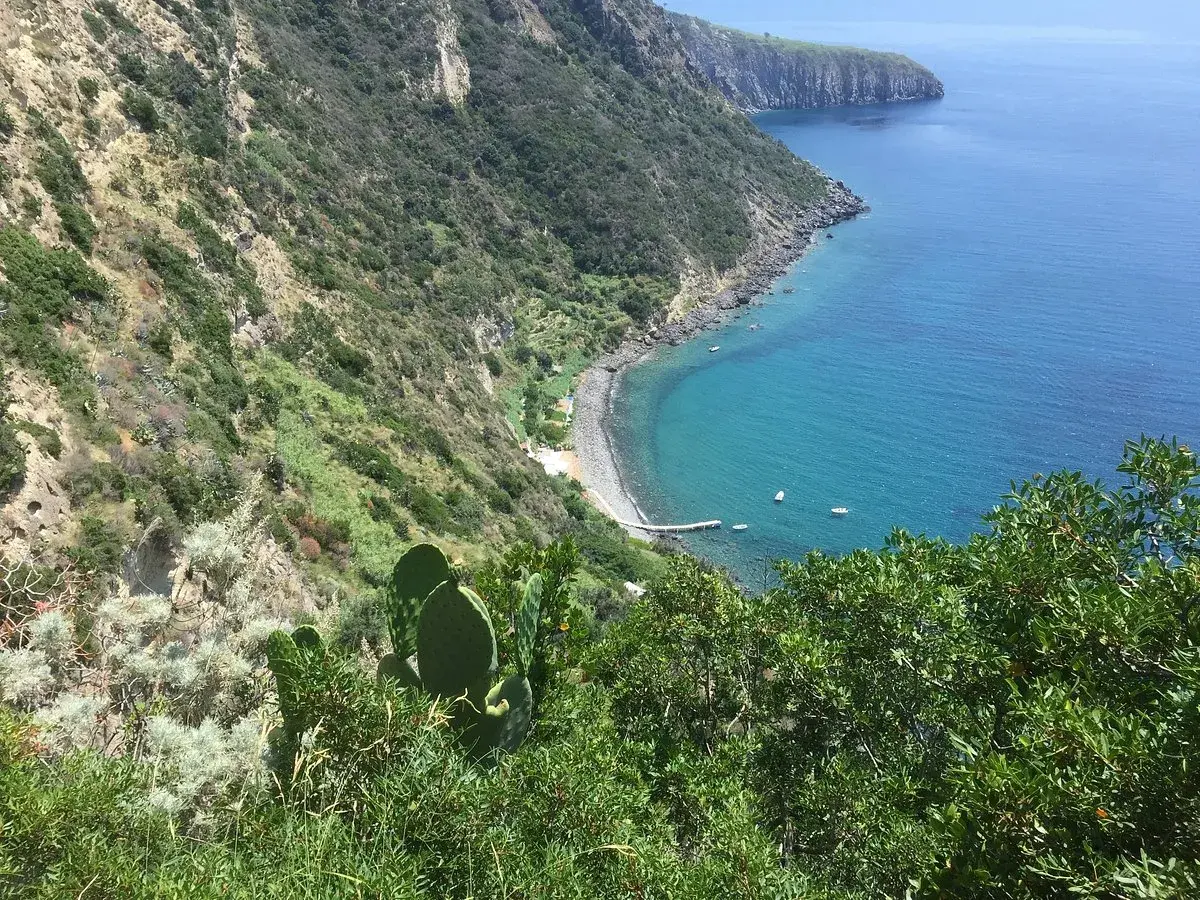 Vista mozzafiato su una baia con acque cristalline e vegetazione lussureggiante. La scarrupata a Ischia, un angolo di paradiso selvaggio.