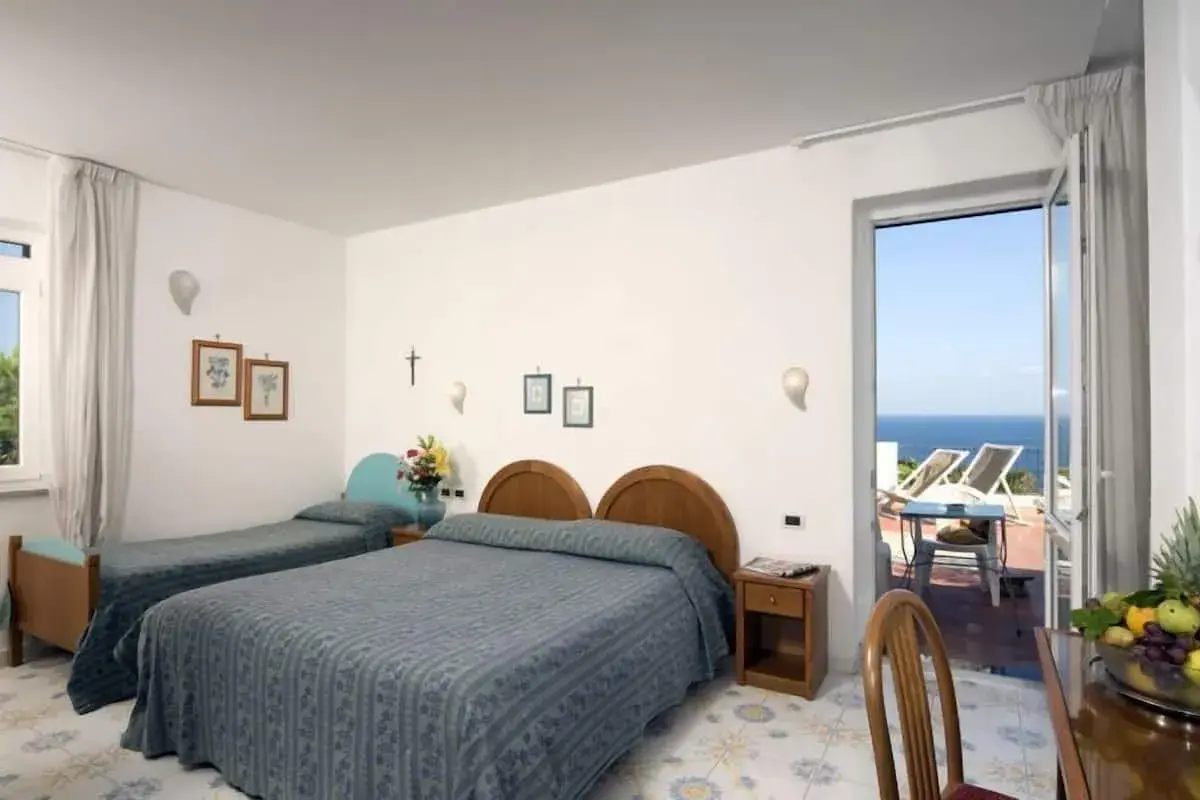 Camera con due letti singoli e un letto matrimoniale, con vista mare dal balcone. L'Hotel Gemma offre un soggiorno rilassante.