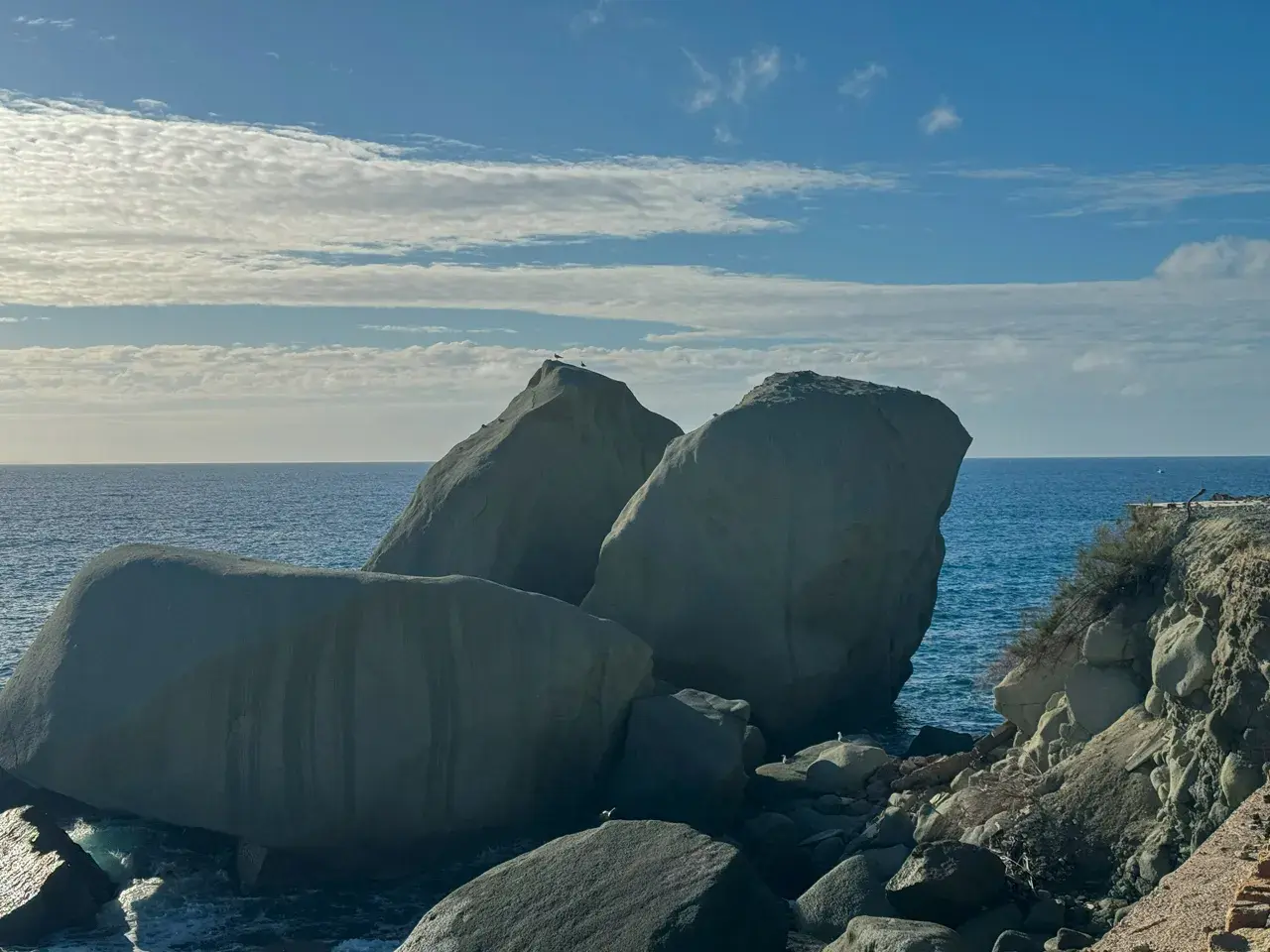 Scogli degli innamorati baciati dal sole, con il mare blu e nuvole bianche nel cielo.