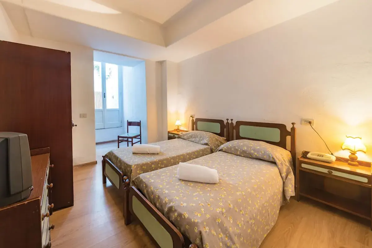 Camera doppia con letti singoli al Hotel Antonella Ischia, con biancheria a fiori e comodini in legno.