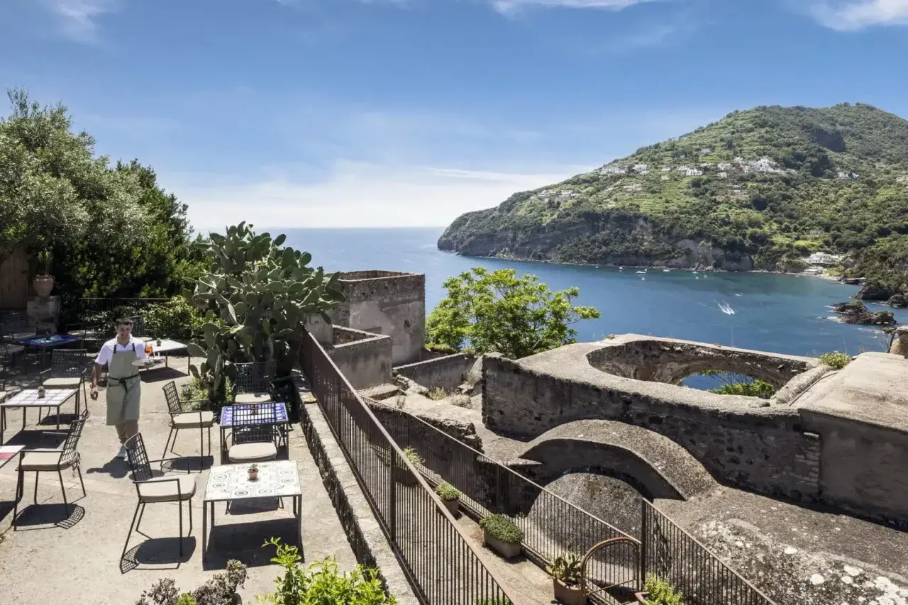 Terrazza con vista mare e un cameriere che serve ai tavoli. Un luogo incantevole, un albergo il monastero con un panorama mozzafiato.