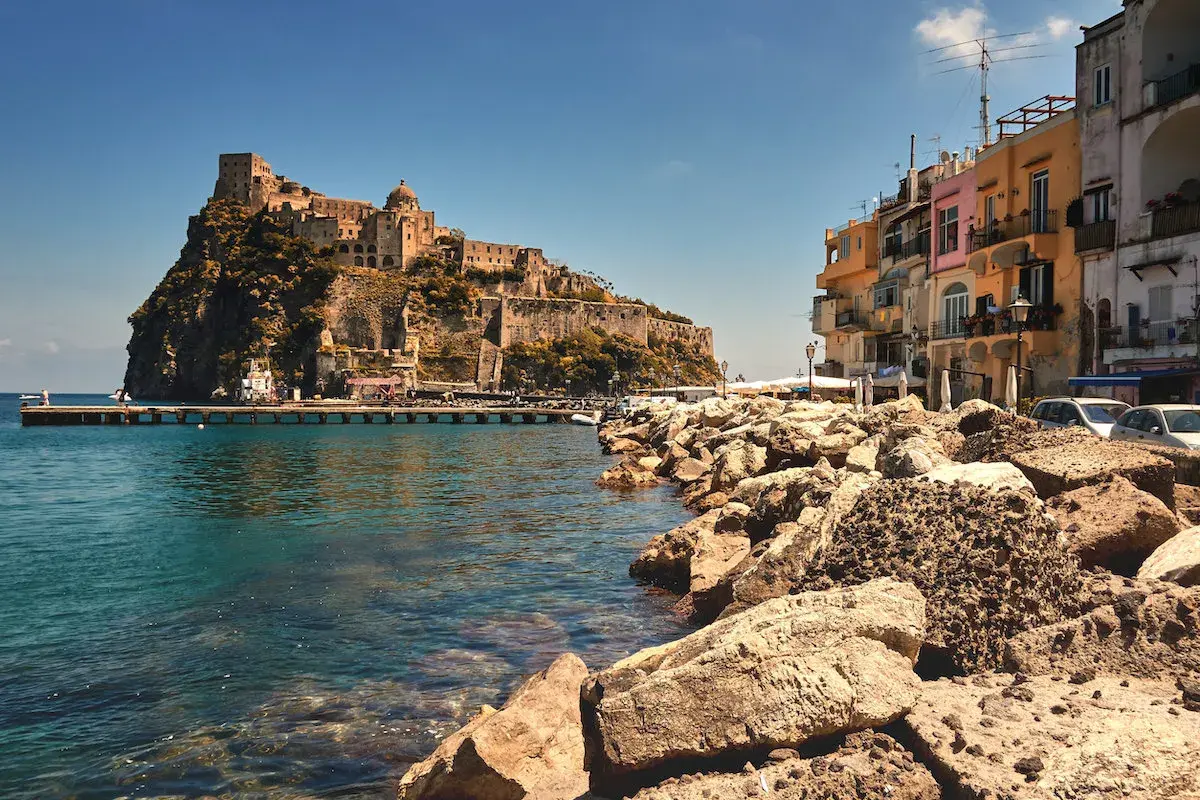 Castello Aragonese su uno scoglio, case colorate e mare cristallino. Chissà come si chiamano gli abitanti di Ischia, i veri protagonisti di questo scorcio.