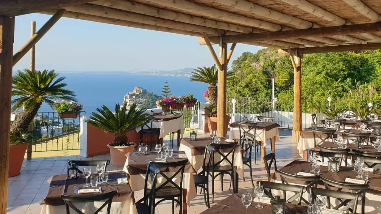 Terrazza con tavoli apparecchiati e vista mare a Ischia. Un vero nascondiglio dell'amore, perfetto per una cena romantica.