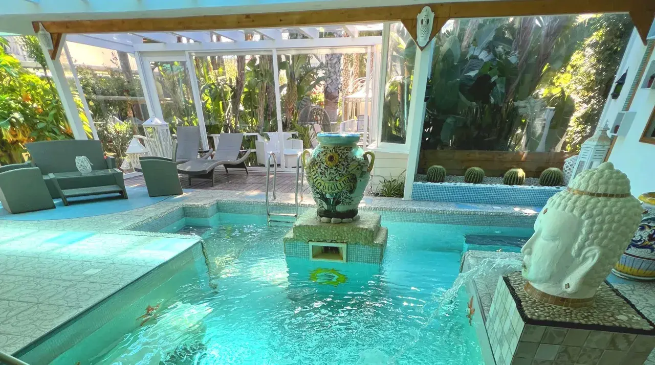 Piscina interna con idromassaggio e fontana a forma di testa di Buddha, decorata con un vaso antico. Relax al **hotel la villa Ischia**.