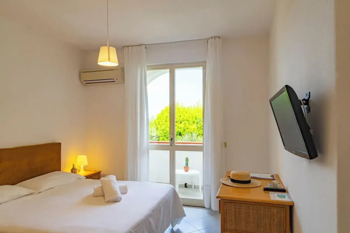 Camera accogliente al paradise relais villa janto, con letto comodo, TV e balcone con vista sul verde.
