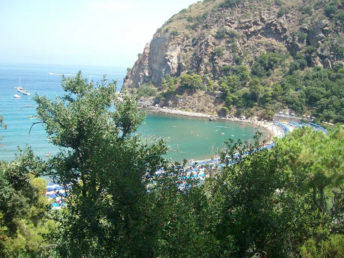 Vista dall'alto della spiaggia di San Montano, con ombrelloni colorati, gente che prende il sole e si gode il mare turchese.