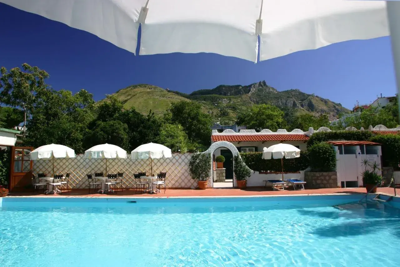 Piscina e tavoli all'aperto con vista sulle montagne, un angolo di relax all'hotel Lord Byron Forio.