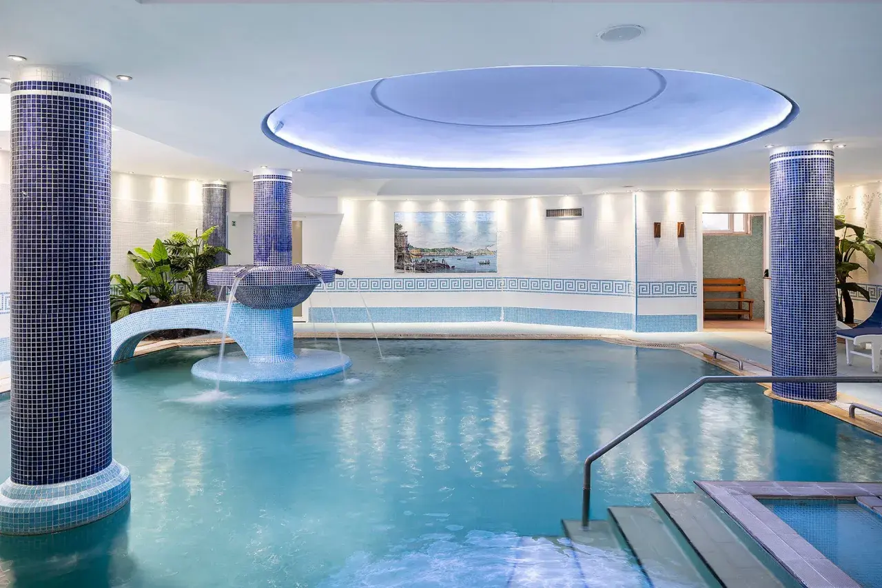 Piscina interna con cascata e piante, un'oasi di relax in uno spa a Ischia.