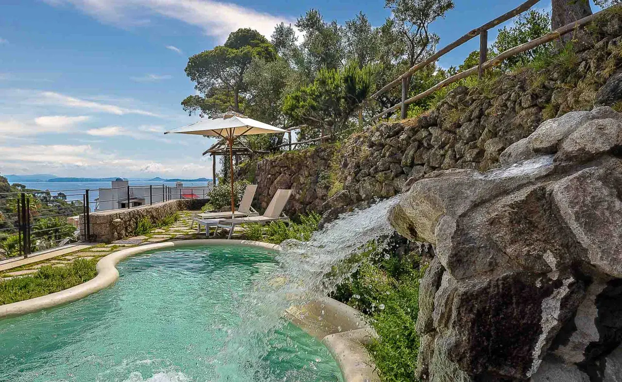 Piscina con cascata e vista mare, ideale per scoprire cosa curano le terme di Ischia. Relax e benessere assicurati.