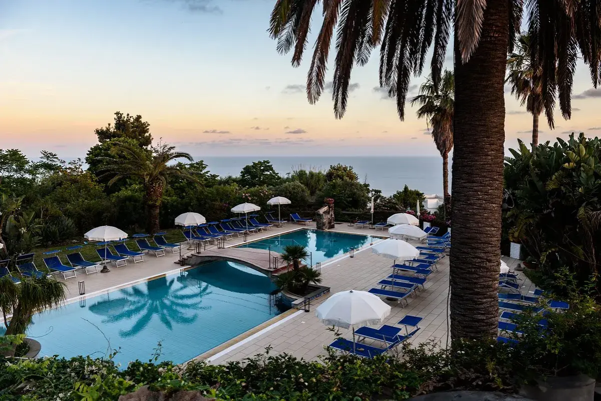 Piscina con lettini e ombrelloni al tramonto, vista mare. Un'oasi di relax all'Hotel Calitto Ischia.
