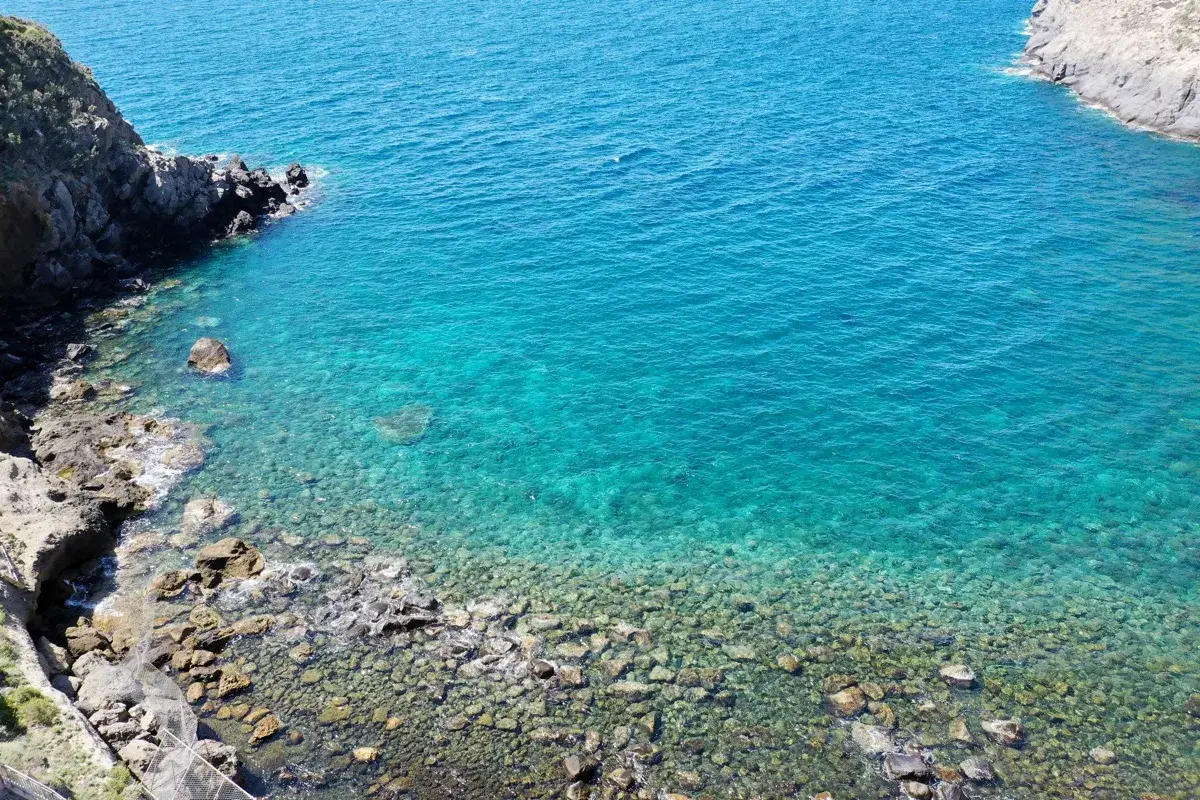 Acque cristalline e scogli a Ischia, un invito a scoprire come muoversi a Ischia via mare o a piedi tra sentieri panoramici.