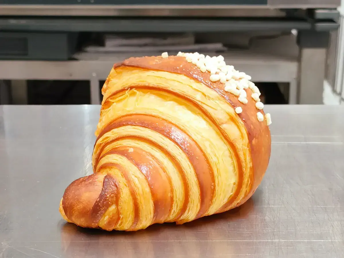 Un delizioso dolce tipico di Ischia, un croissant sfogliato e dorato, cosparso di perline di zucchero croccanti.