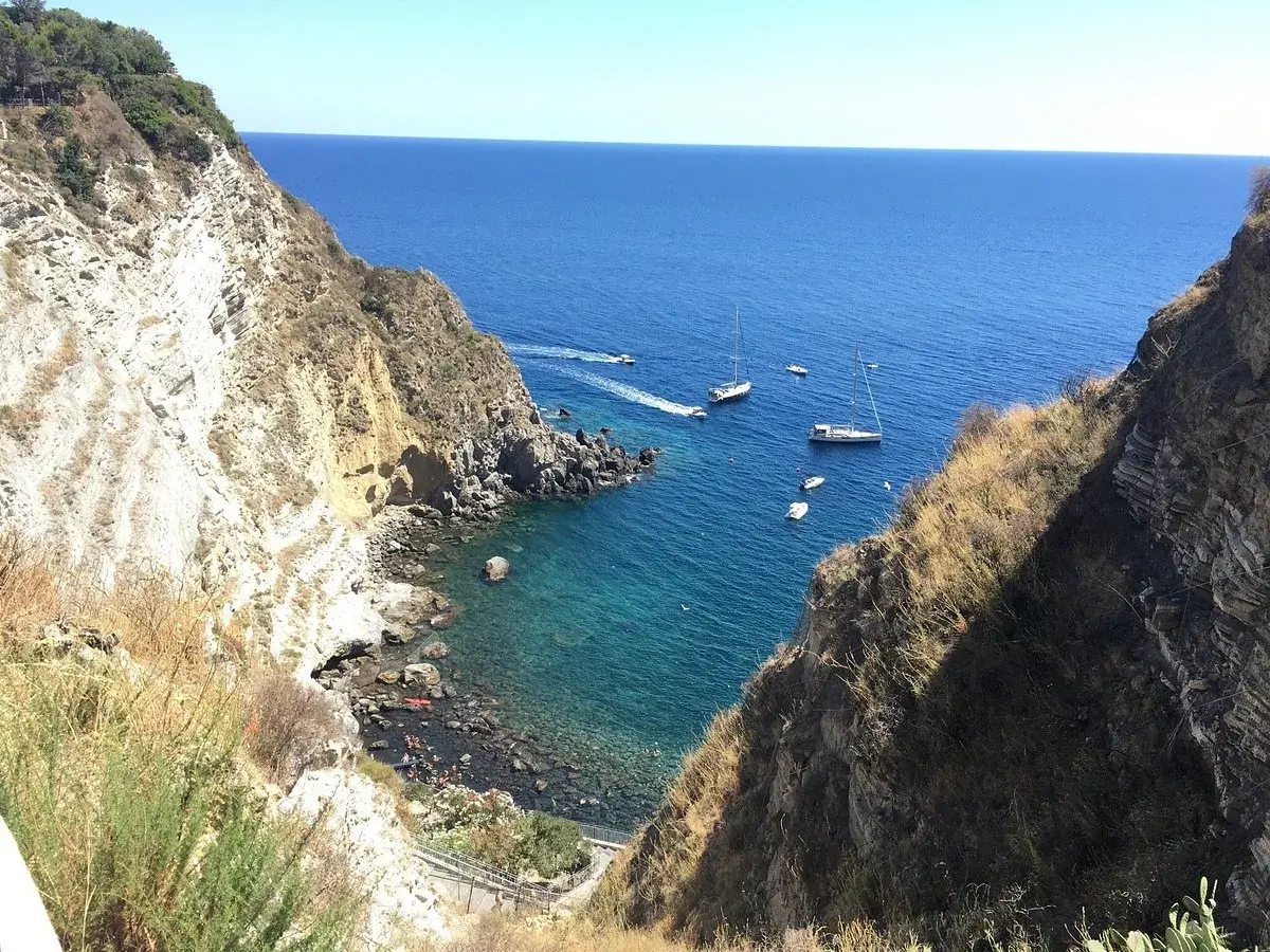 Baia di Panza, Ischia: scogliere a picco sul mare blu, barche a vela e un angolo di paradiso per nuotare.