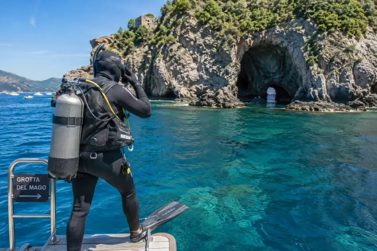Angelo Rizzoli si prepara a esplorare la Grotta del Mago a Ischia, con le sue acque cristalline e la costa rocciosa.