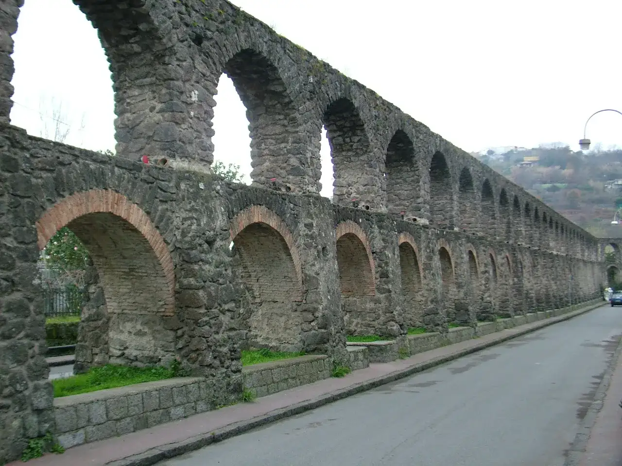 Antichi pilastri in pietra e mattoni a Ischia, un acquedotto imponente che si estende lungo la strada.