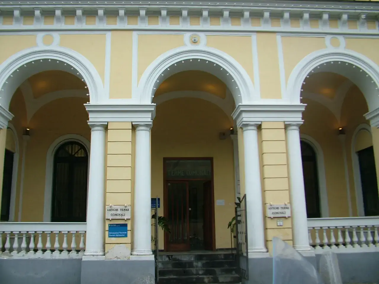Ingresso delle antiche terme comunali di Ischia, con archi bianchi e colonne imponenti.