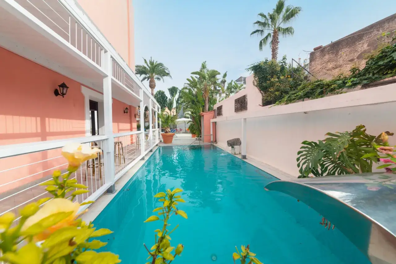 Piscina azzurra e palme rigogliose nel cortile di zi Carmela, un angolo di paradiso baciato dal sole.