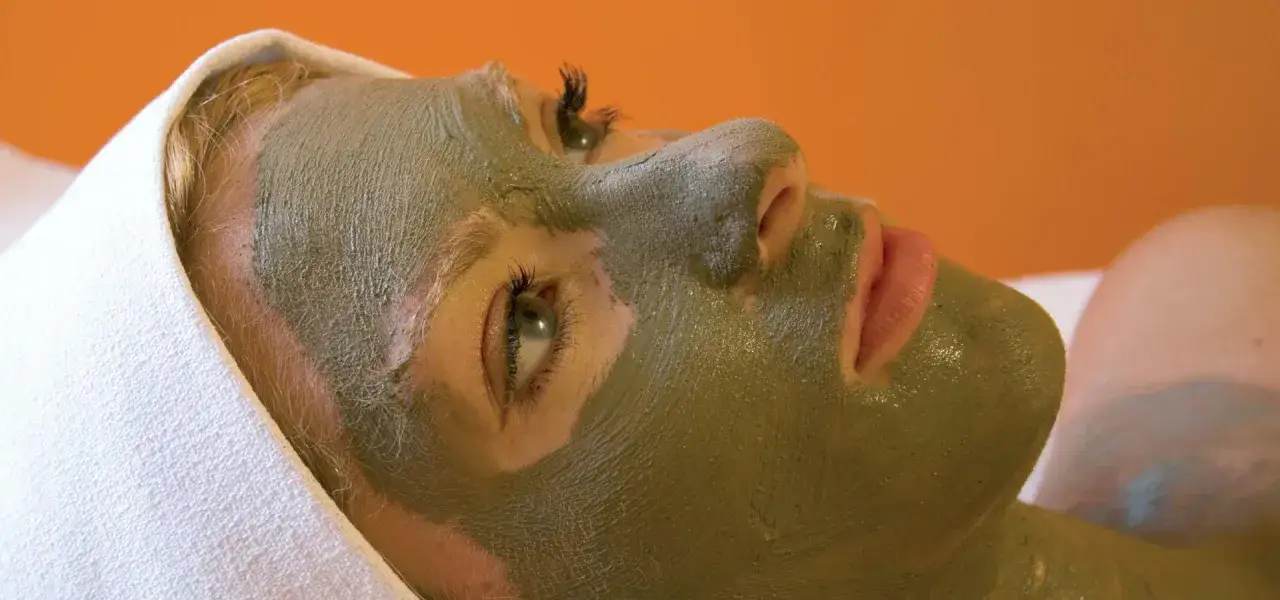 Donna con maschera ai fanghi termali d'Ischia, avvolta in un asciugamano bianco.