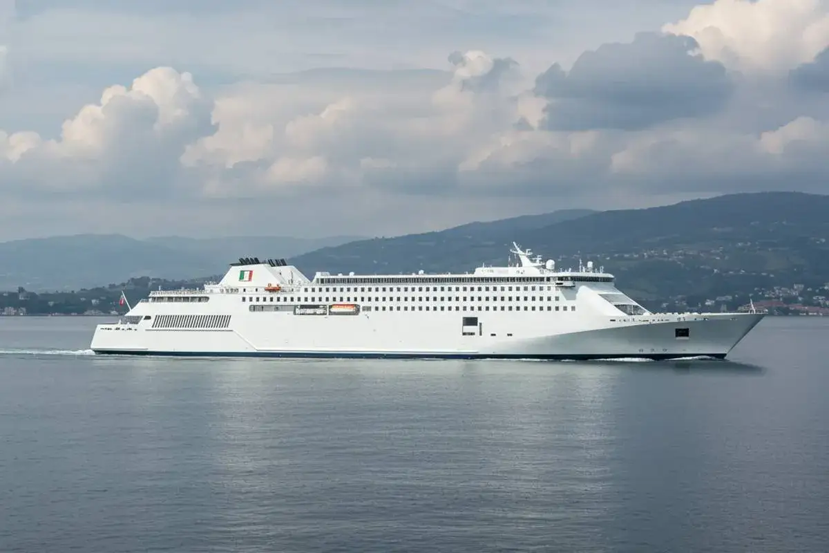 Traghetto bianco con bandiera italiana naviga sul mare, pronto per il viaggio da Sorrento a Ischia.