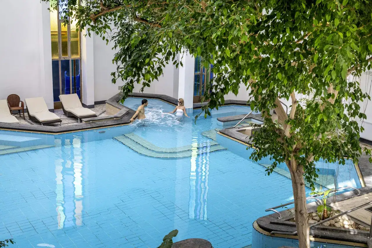 Coppia rilassata nella piscina termale dell'Hotel La Reginella Ischia, un'oasi di benessere che conferma le ottime recensioni.