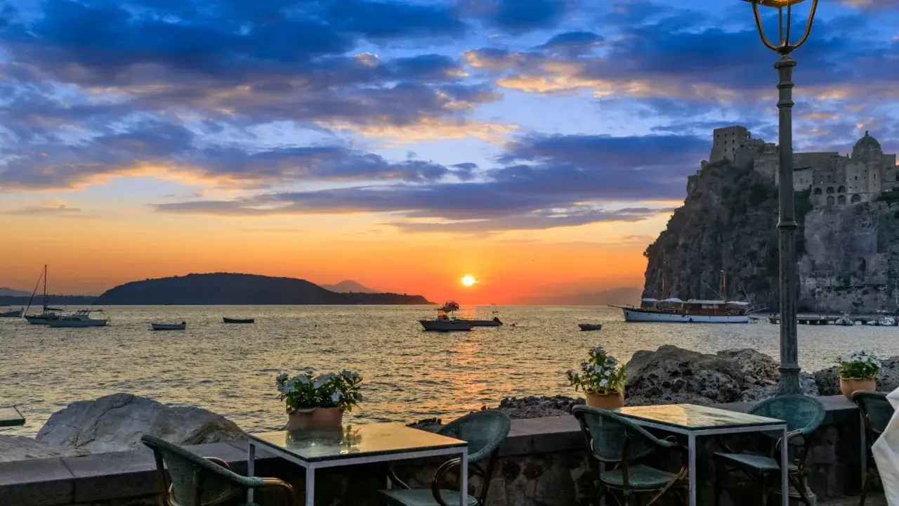 Tramonto a Ischia con il Castello Aragonese sullo sfondo. Un invito a scoprire cosa vedere a Ischia, tra mare e storia.