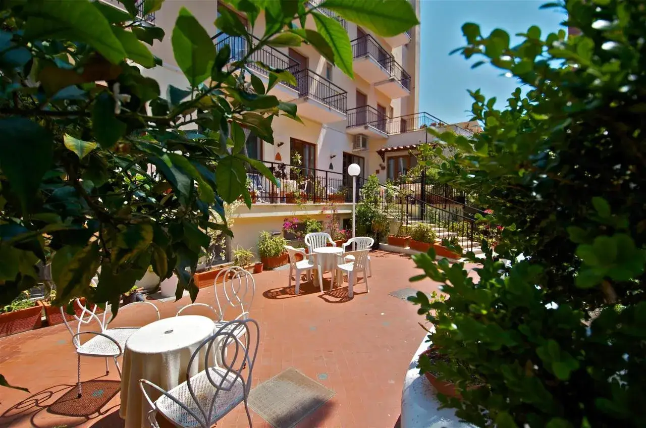Terrazza fiorita con tavoli e sedie, ideale per un caff&egrave; mattutino al hotel Conte Ischia.