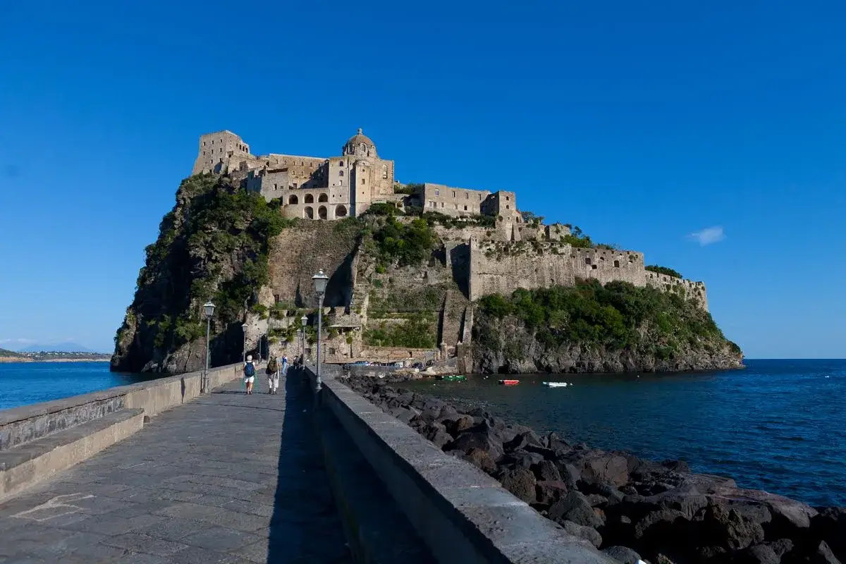 Ponte pedonale verso il Castello Aragonese di Ischia, un'imponente fortezza su un isolotto roccioso.