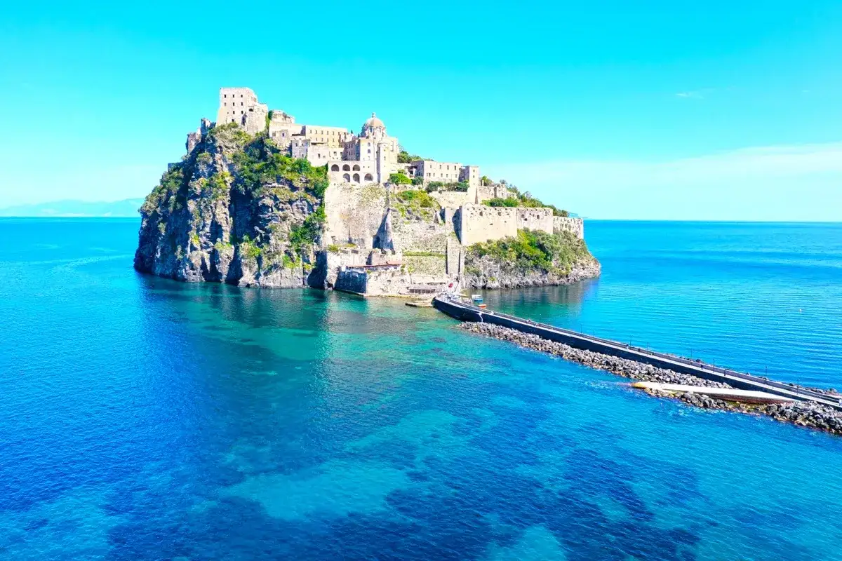 Il Castello Aragonese si trova su un isolotto roccioso, collegato da un molo, con il mare azzurro e limpido che lo circonda.